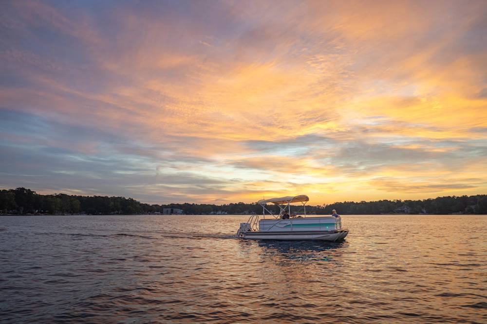 Pontoon boat on a calm lake at sunset