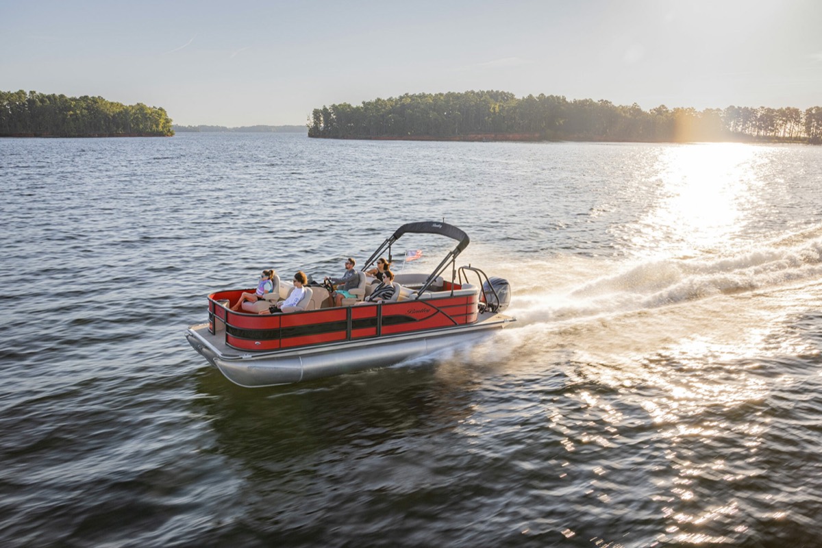 Family cruising a lake on a pontoon boat